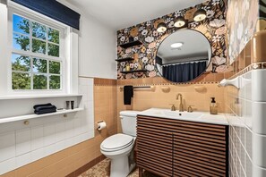 A bathroom with a toilet, sink, and window. - Hilltop Charm — 4BR house in Menomonie (Menomonie)