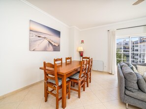 A dining area with a wooden table and chairs, a painting on the wall, a lamp, and a view of buildings through a window. - Spacious Stylish Apartment near Lagos Centre (Lagos)