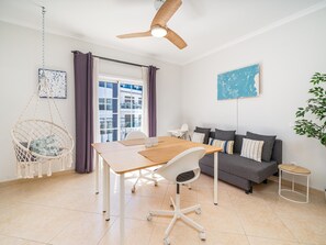 A modern living room with a wooden dining table, a grey sofa, a macramé chair, and a ceiling fan. - Spacious Stylish Apartment near Lagos Centre (Lagos)