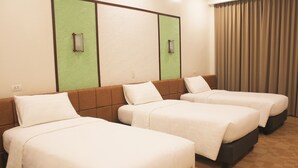 A hotel room with three beds arranged in a row, a large window with curtains, and a wall with a green panel and a light switch. - Port Royale Waterpark Resort Tacloban (Tacloban)