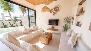 Una sala de estar moderna con un sofá grande, una mesa de centro y un televisor montado en la pared.