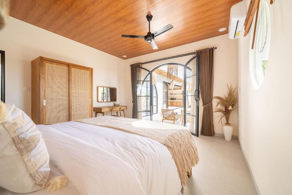 Een slaapkamer met een bed, een plafondventilator, een bureau en uitzicht op het omliggende landschap.