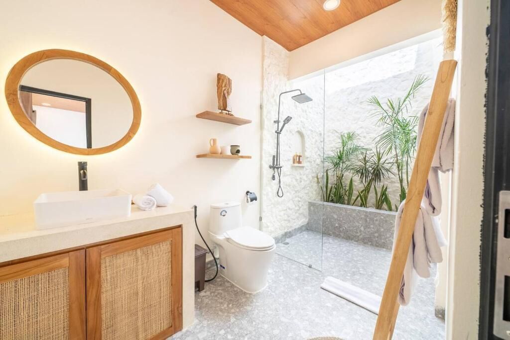 A modern bathroom with a freestanding toilet, a sink with a mirror, and a shower area with a glass door.