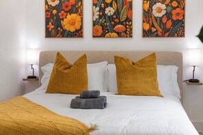 Ein Hotelzimmer mit einem Bett, zwei Kissen, einer Decke und drei an der Wand hängenden Bildern.