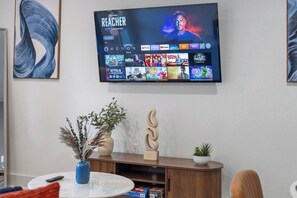 Ein Flachbildfernseher an der Wand, der eine Streaming-Oberfläche mit verschiedenen Serien und Filmen zeigt.