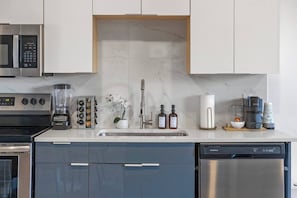 Eine moderne Küche mit Edelstahlgeräten, einer Marmor-Spritzschutzwand und einem Geschirrspüler.