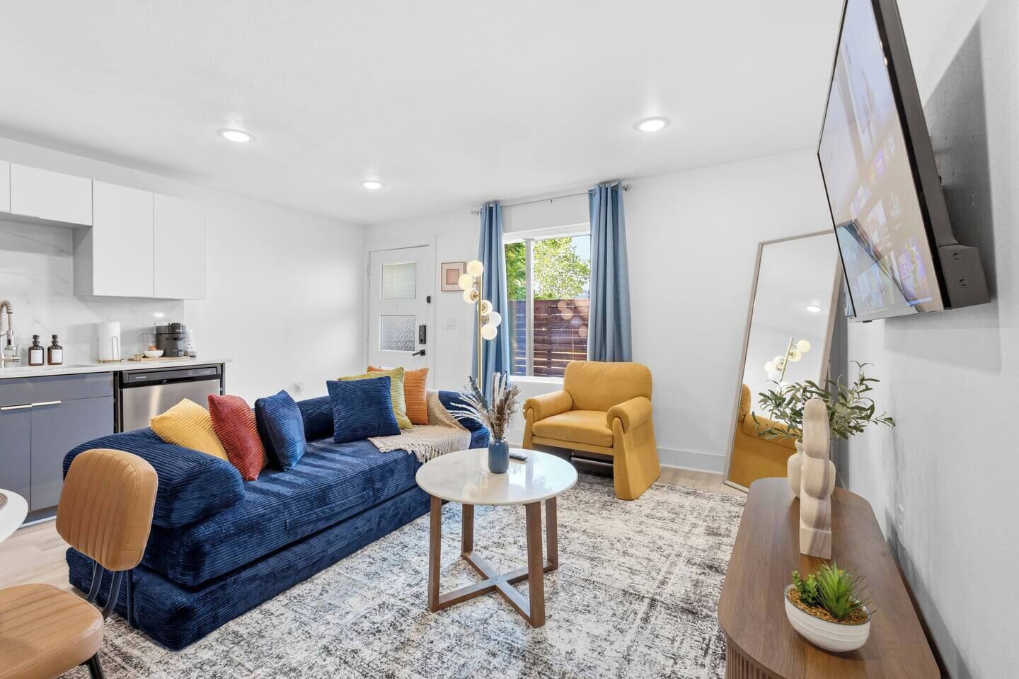 A modern living room with a sofa, armchairs, a coffee table, and a TV mounted on the wall.