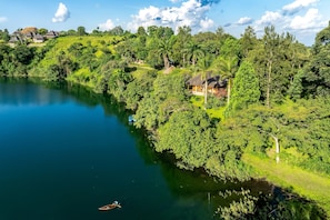 A riverside property with a house surrounded by lush greenery and a clear view of the river. - bahundu Safari Lodge (Fort Portal)