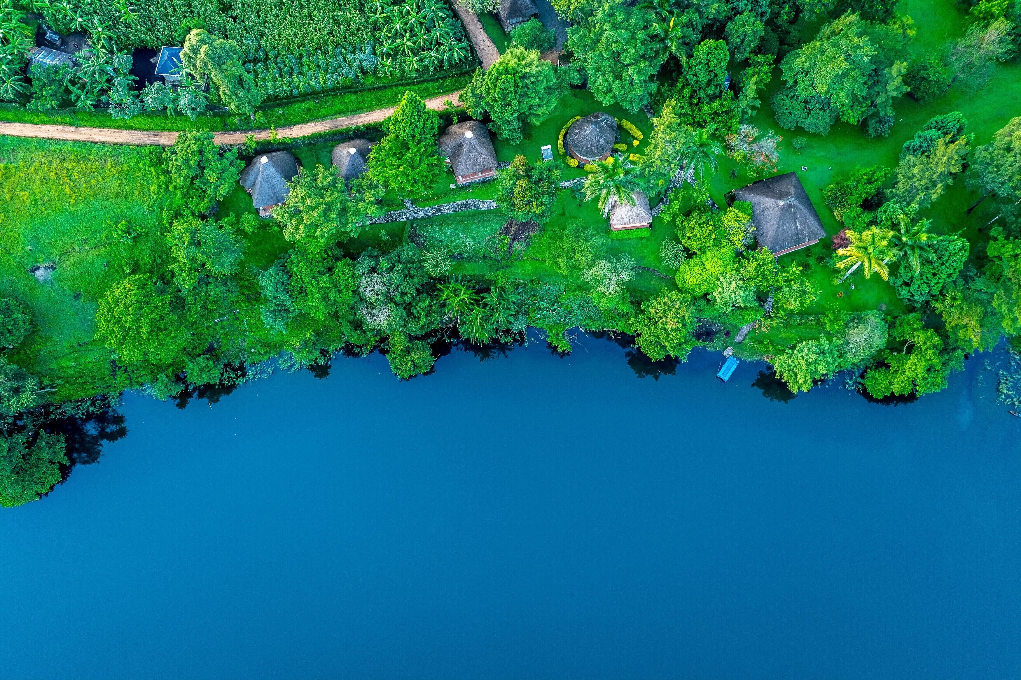 Oversigtsbillede af et resort med flere bungalows omgivet af frodig vegetation og et vandareal.