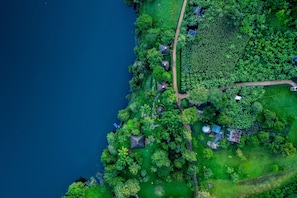 Vista aérea de una propiedad costera con playa, abundante vegetación y algunas construcciones.