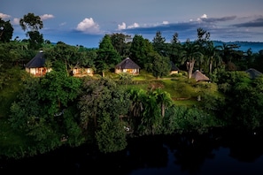 A cluster of thatched-roof cottages surrounded by dense tropical vegetation. - bahundu Safari Lodge (Fort Portal)
