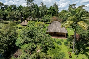 A tropical resort with thatched-roof huts surrounded by lush greenery and palm trees. - bahundu Safari Lodge (Fort Portal)