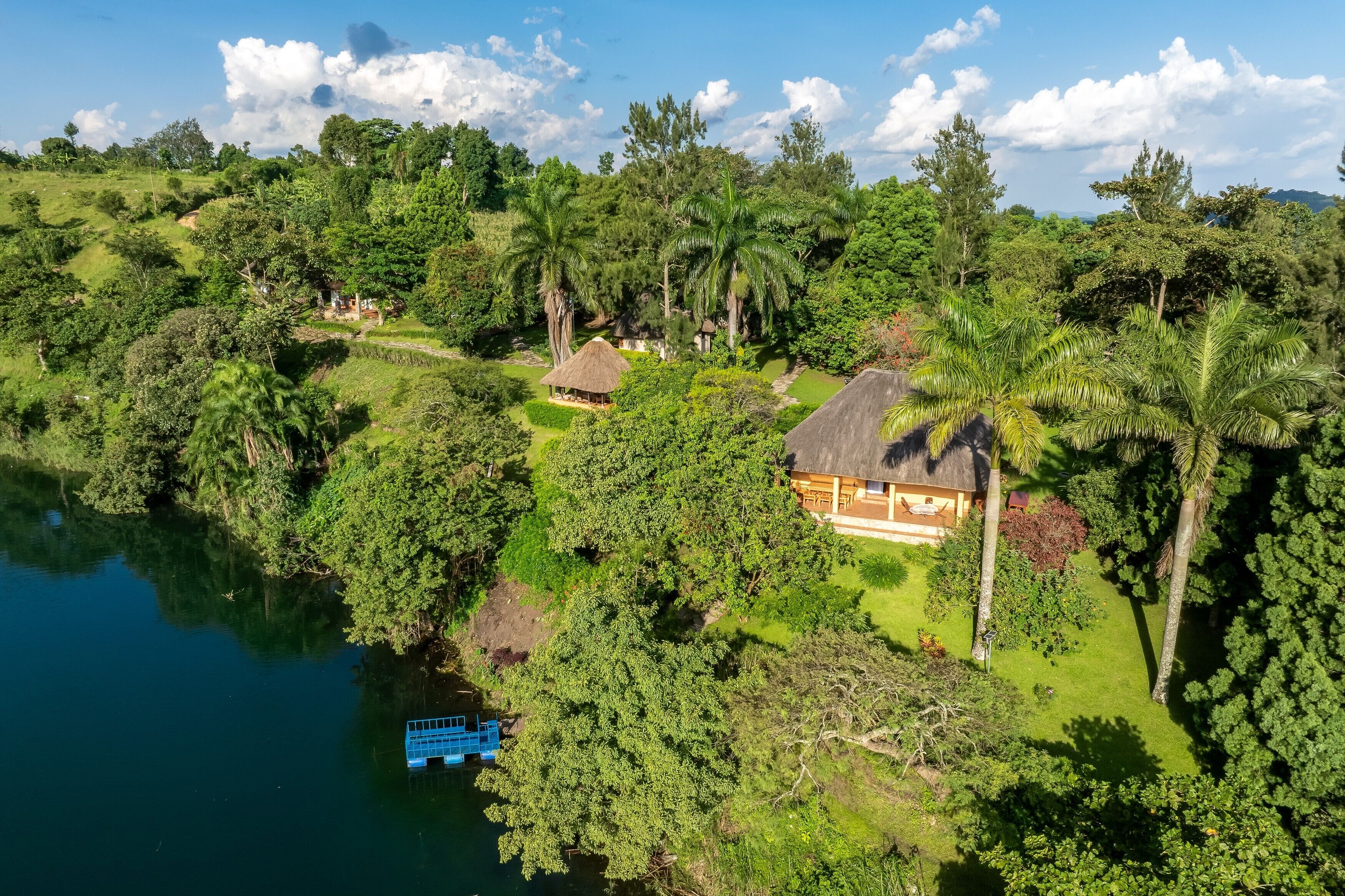 A tropical resort with thatched-roof cottages, a swimming pool, and lush greenery.