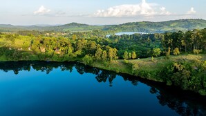 A serene landscape with a calm lake reflecting the surrounding greenery and distant hills.