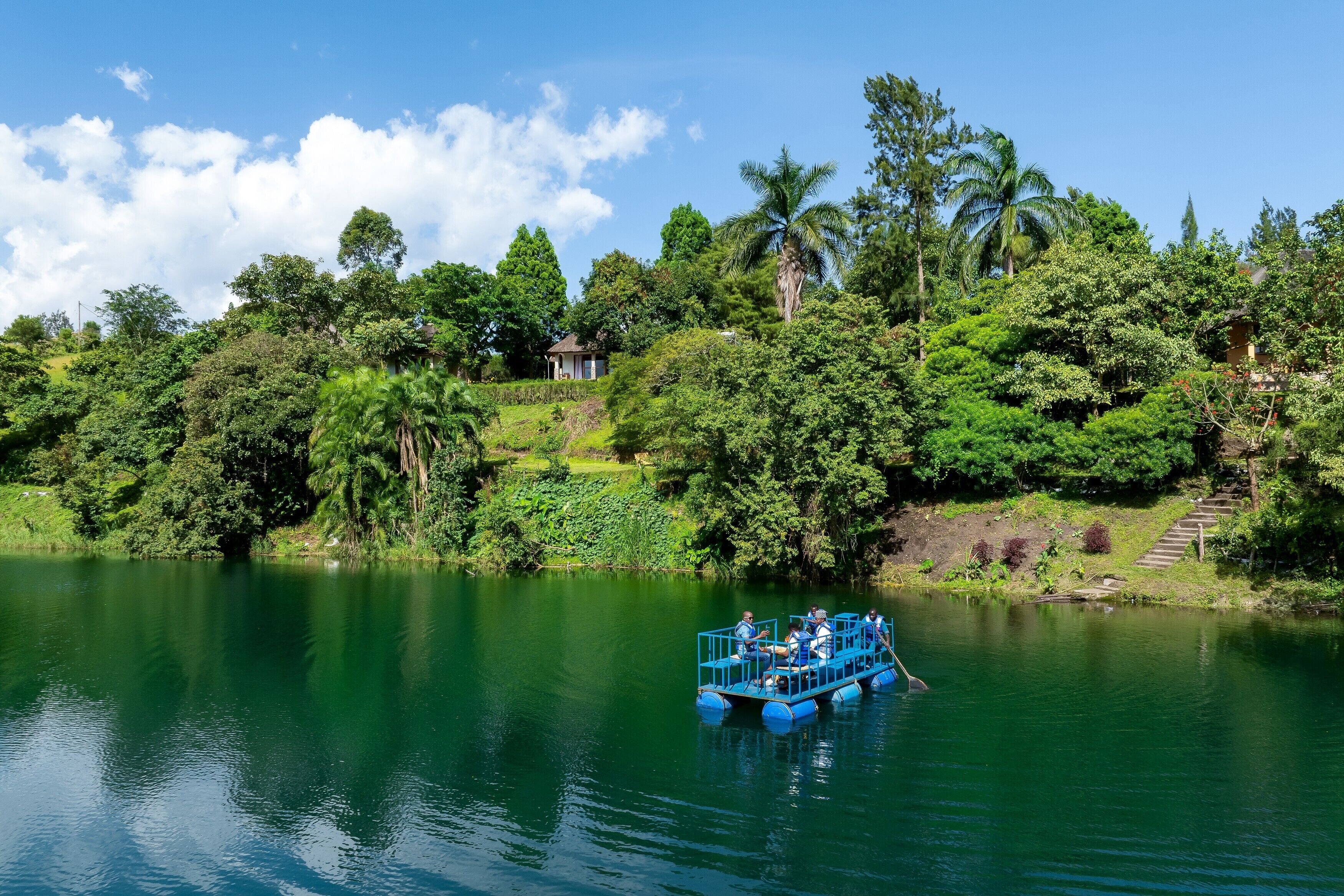 A boat with passengers on a calm lake surrounded by lush greenery and trees.