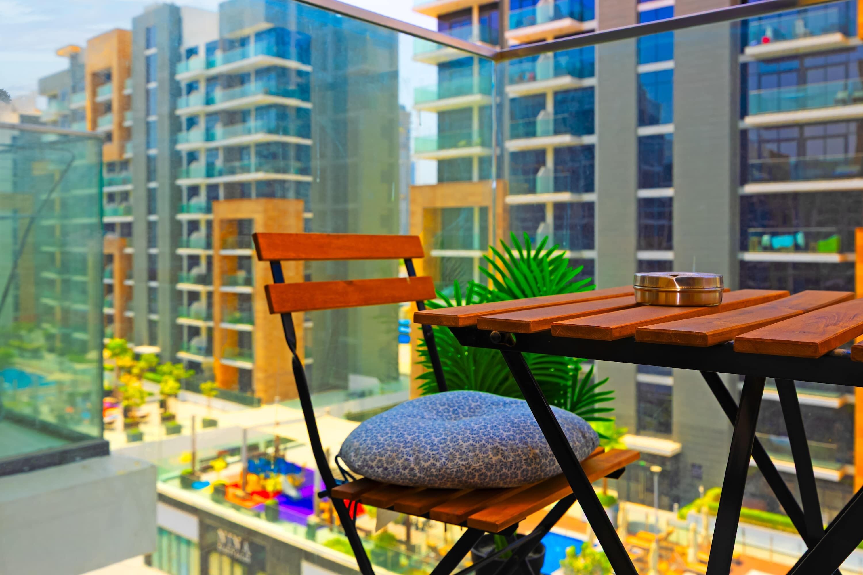 Ein Balkon mit einem Holztisch, einem Kissen und einem Stuhl.