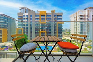 Un balcon avec une table et des chaises, donnant sur un paysage urbain avec des bâtiments modernes.
