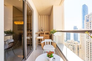 A balcony with a dining area, a table with a potted plant, and a view of city buildings. - Shams 1 JBR 2BR · Marina View · Beach Walk (Dubai)