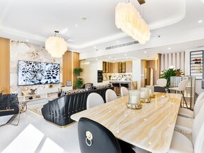 A modern dining area with a marble table, black and white upholstered chairs, and a large chandelier. - Shams 1 JBR 2BR · Marina View · Beach Walk (Dubai)