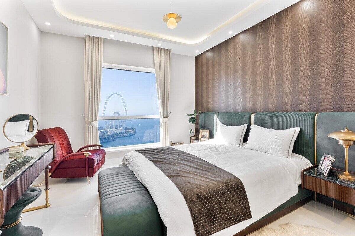 Habitación de hotel moderna con una cama grande, un escritorio con silla, una mesita de noche y vistas a una noria.