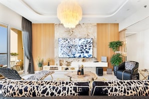A modern living room with a large flat-screen TV, a sofa set, a coffee table, and a chandelier. - Shams 1 JBR 2BR · Marina View · Beach Walk (Dubai)