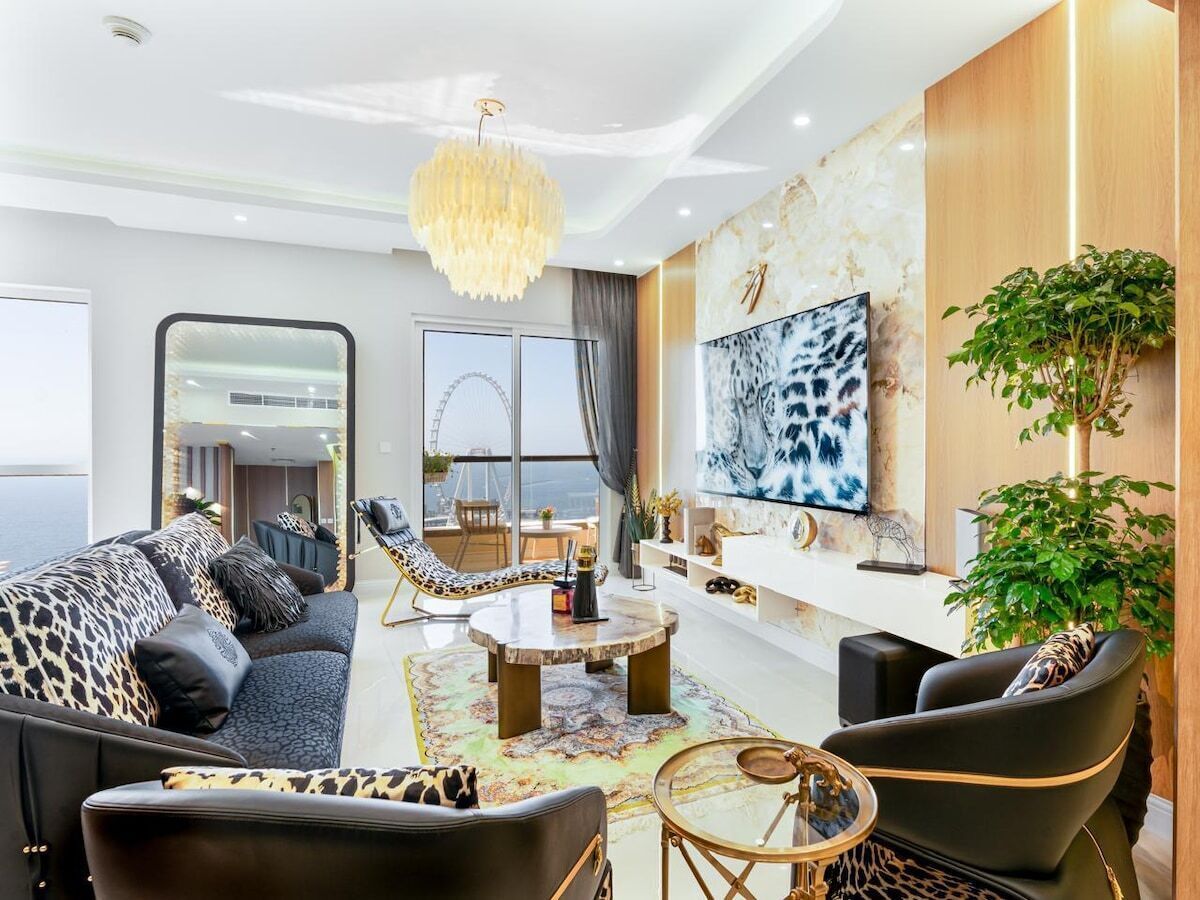 A modern living room with a sofa, chairs, a coffee table, and a large TV.