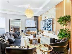 A modern living room with a sofa, chairs, a coffee table, and a large TV. - Shams 1 JBR 2BR · Marina View · Beach Walk (Dubai)
