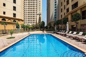 A swimming pool with lounge chairs and a fence, surrounded by buildings. - Shams 1 JBR 2BR · Marina View · Beach Walk (Dubai)