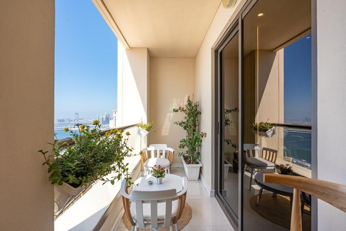 Un balcon avec une table et des chaises, des plantes en pot et une vue sur la ville.