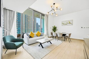 A modern living room with a sofa, armchair, coffee table, dining table, and chairs. - LIV Marina 2BR · City View · Beach 5min (Dubai)