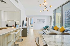 A modern apartment with a kitchen, dining area, and living room. There is a large window providing a view of the city. - LIV Marina 2BR · City View · Beach 5min (Dubai)