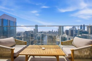 A balcony with a wooden table and two chairs, overlooking a cityscape with modern buildings. - Imperial 3BR · Canal View · Downtown (Dubai)
