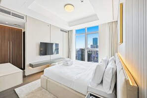 Habitació d'hotel moderna amb un llit gran, un televisor de pantalla plana, vista a la ciutat i un armari integrat.