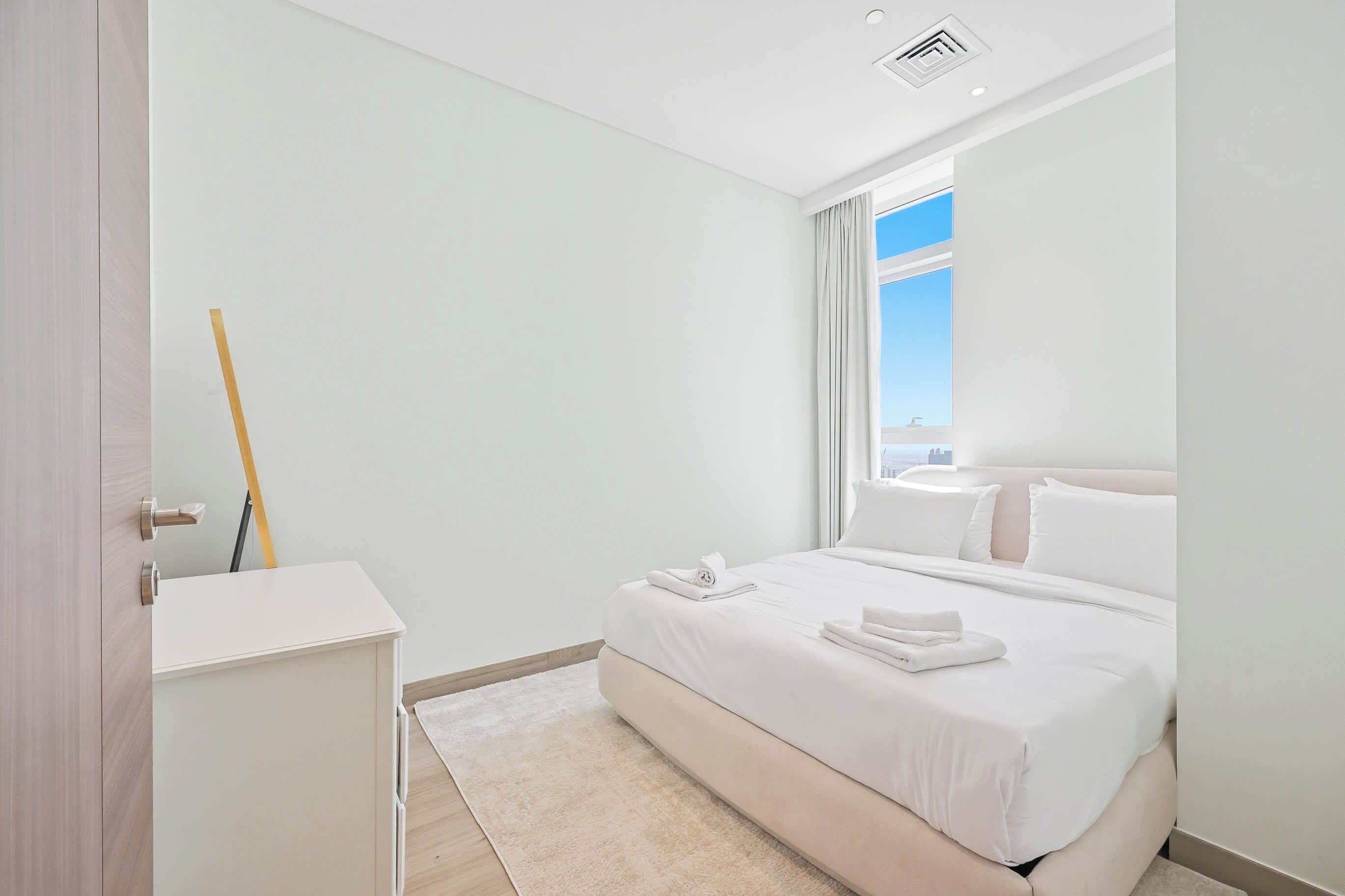 A modern hotel room with a large bed, a desk, and a view of the city.
