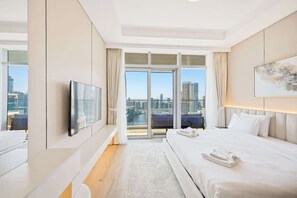 A hotel room with a bed, a television, a view of the cityscape, and a balcony. - Imperial 3BR · Canal View · Downtown (Dubai)