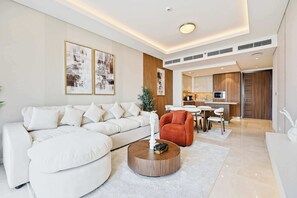 Un saló modern amb un sofà blanc, una taula de centre rodona de fusta i un butac armchair vermell.