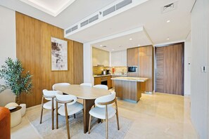A modern kitchen with a central island, white cabinetry, and a built-in microwave. - Imperial 3BR · Canal View · Downtown (Dubai)