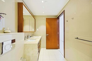 A modern bathroom with a wooden door, two sinks, and a large mirror. - Blvd Point 2BR · Burj View · Dubai Mall (Dubai)