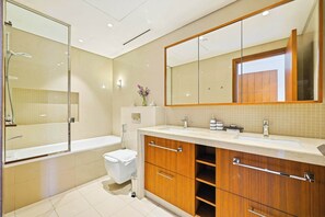 A modern bathroom with a bathtub, a shower, a toilet, and a vanity with a mirror. - Blvd Point 2BR · Burj View · Dubai Mall (Dubai)