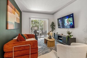 A modern living room with a sofa, a TV, and a view of the outdoors.