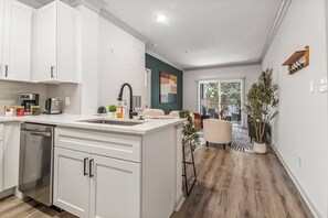 A modern kitchen with white cabinetry, a built-in dishwasher, and a coffee machine.
