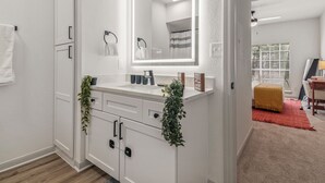 Une salle de bain moderne avec un meuble-lavabo blanc, un grand miroir et un porte-serviettes.
