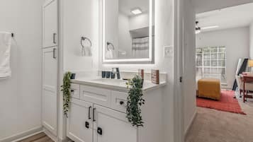 A modern bathroom with a white vanity, a large mirror, and a towel rack.