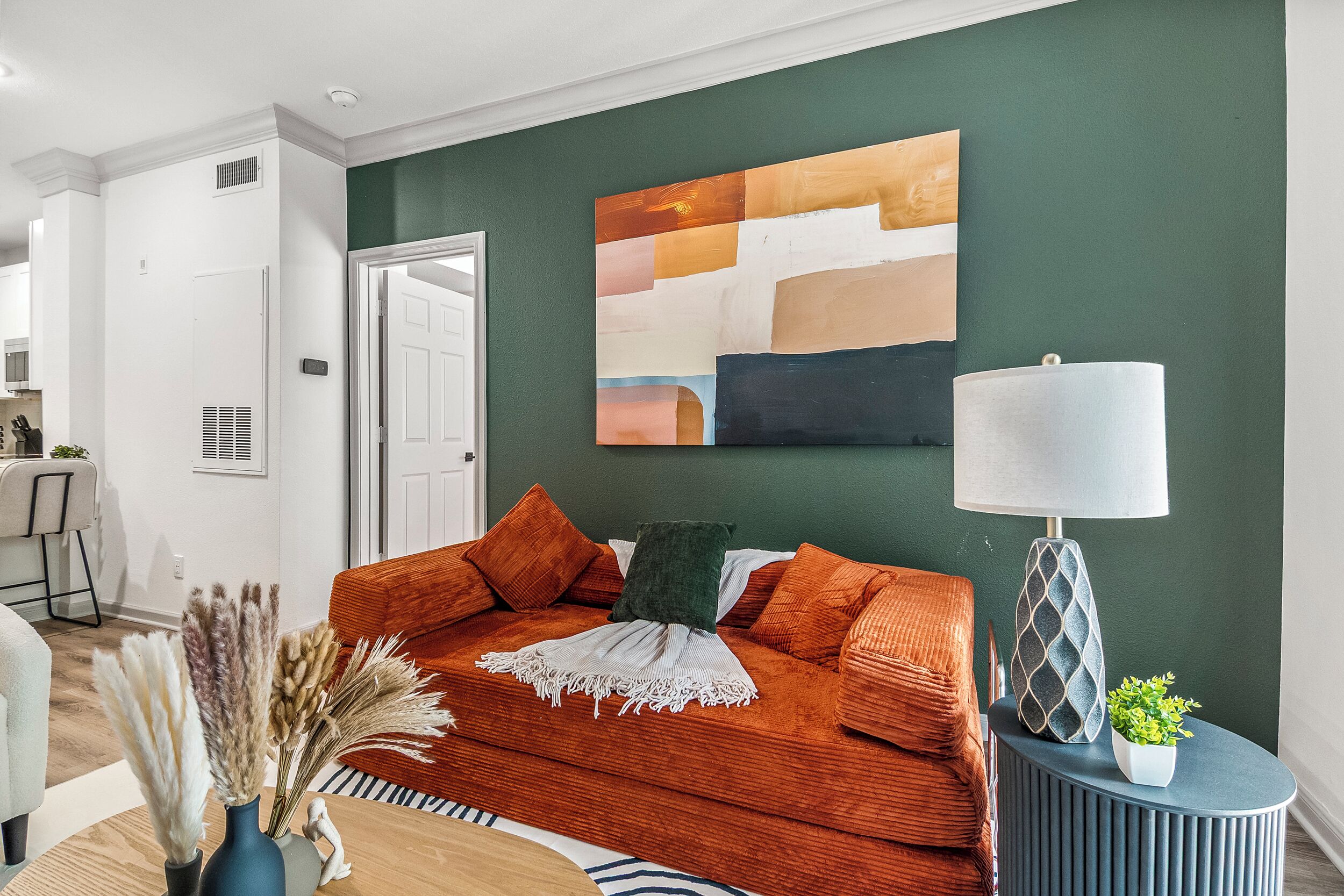 A living room with a sofa, a lamp, and a painting on the wall.