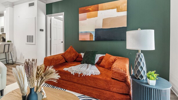 Un salon avec un canapé, une lampe et un tableau au mur.