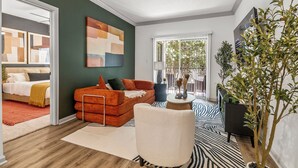 Un salon moderne avec un canapé, un fauteuil, une table basse et une grande fenêtre.