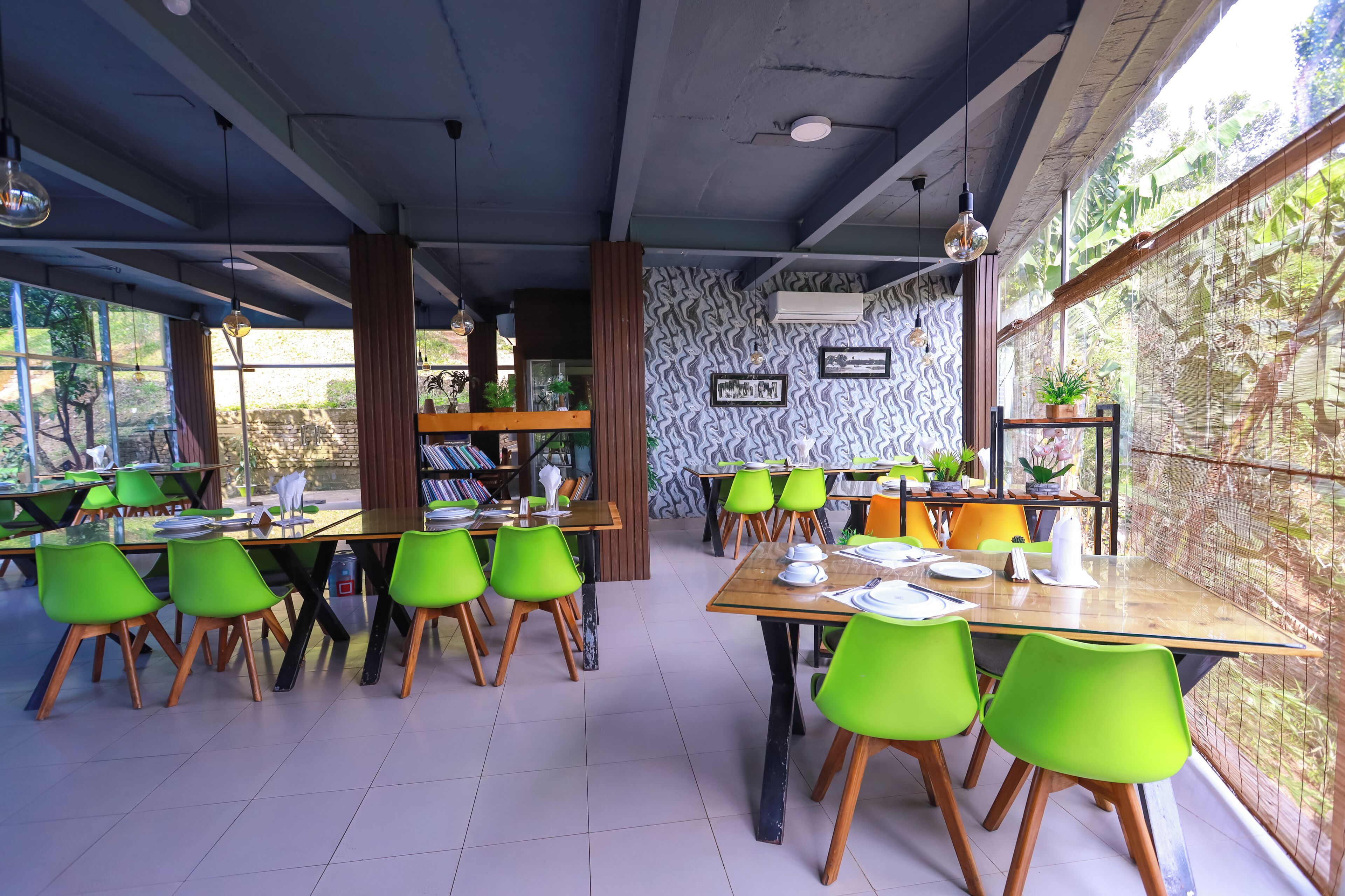 Un restaurante con varias mesas y sillas, ventanas amplias y un papel tapiz decorativo.