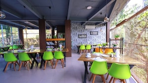 Un restaurante con varias mesas y sillas, ventanas amplias y un papel tapiz decorativo.