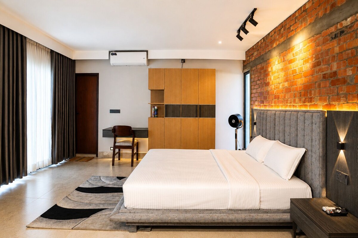 Een moderne slaapkamer met een groot bed, een bureau en een metselwerk muur.