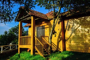 A wooden cabin with a porch, a staircase, and a door.
